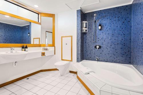 a bathroom with a tub and a toilet and a sink at Quality Hotel Lincoln Green in Auckland