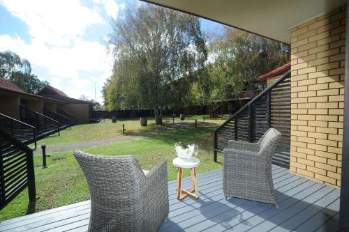 a porch with three chairs and a table with a vase on it at Quality Hotel Lincoln Green in Auckland
