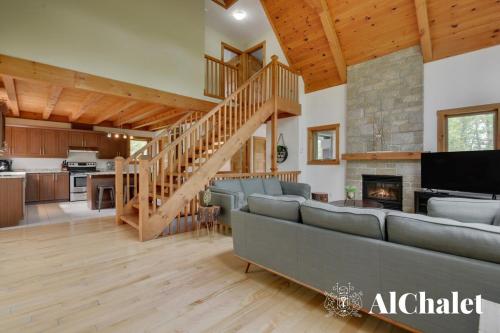 a living room with a couch and a staircase at Chalet A-Évasion- Holidays & Spa in Petite-Rivière-Saint-François
