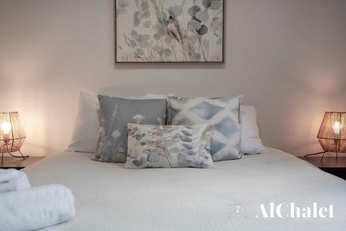 a bed with blue and white pillows on it at Chalet A-Évasion- Holidays & Spa in Petite-Rivière-Saint-François