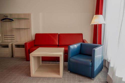 a living room with a red couch and a blue chair at Park Inn by Radisson Linz in Linz