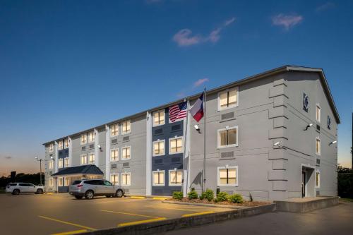 a building with two american flags in a parking lot at SureStay Hotel by Best Western Groves in Groves