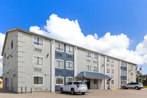 a large building with two cars parked in a parking lot at SureStay Hotel by Best Western Groves in Groves
