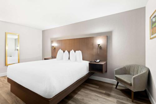 a hotel room with a large bed and a chair at SureStay Hotel by Best Western Groves in Groves