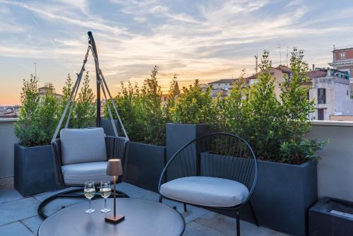 a patio with two chairs and wine glasses on a balcony at Hotel Raffaello - Sure Hotel Collection by Best Western in Rome