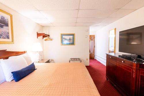 a hotel room with a bed and a flat screen tv at Fireside Inn and Suites Bangor in Bangor