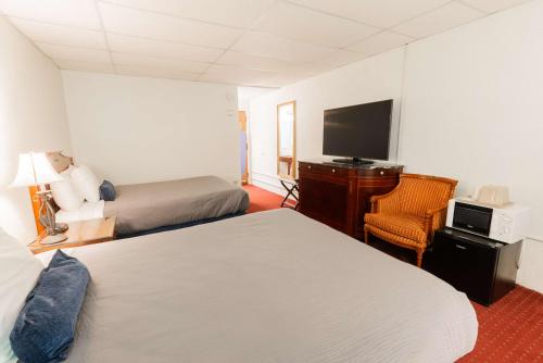 a hotel room with two beds and a flat screen tv at Fireside Inn and Suites Bangor in Bangor