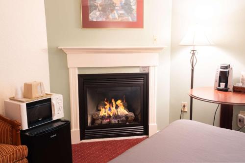a living room with a fireplace with a microwave at Fireside Inn and Suites Bangor in Bangor