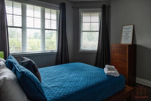 a bedroom with a bed with blue sheets and windows at Le Champlain 101- Condo avec Piscine in Bromont