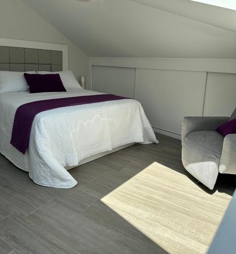 a bedroom with a bed and a chair and a rug at Ático mirando o mar in Porto do Son