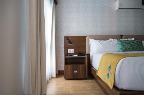 a bedroom with a bed and a night stand with a lamp at FCH Hotel Expo Adults only in Guadalajara