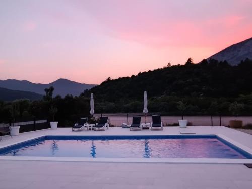 a swimming pool with chairs and a sunset at Villa Krivokapic in Trebinje