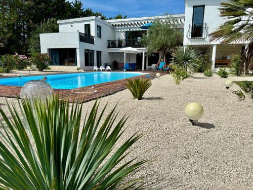 une maison avec une piscine devant une maison dans l'établissement Villa Californienne du soleil, à La Rochelle