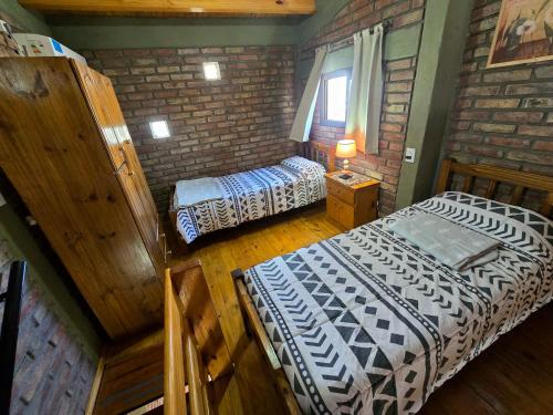 Un dormitorio con dos camas y una pared de ladrillo. en Deseo de Montaña, en Maipú