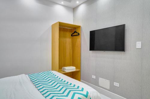 a bedroom with a bed and a flat screen tv at Monaco Residences Piantini in Santo Domingo