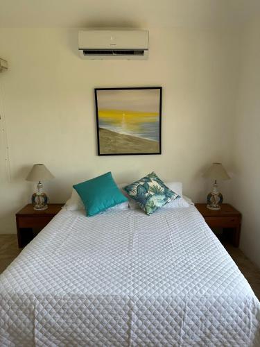 a bedroom with a large white bed with two lamps at Villa in Monterrico in El Garitón