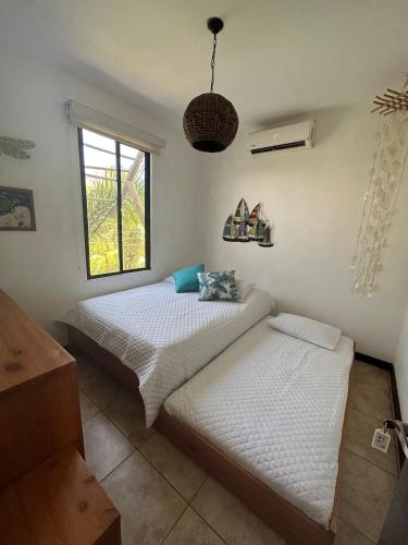 two twin beds in a room with a window at Villa in Monterrico in El Garitón
