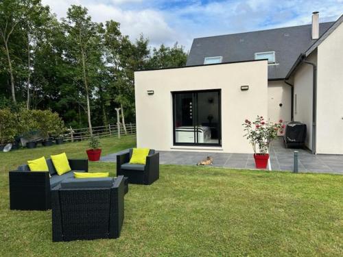 un chien assis dans l'herbe devant une maison dans l'établissement Un Coin Paisible, à Lantheuil