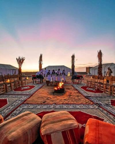 a group of people sitting around a fire in a tent at Camel Luxury Camp in Merzouga