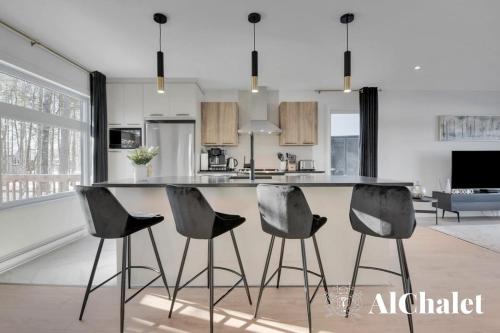 a kitchen with a island with four chairs in it at Forêt Blanche - Sauna et Spa in Pont-Rouge