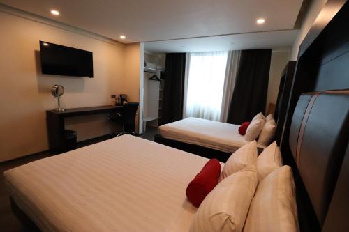 a hotel room with two beds and a television at Best Western Plus Metepec & Suites in Toluca