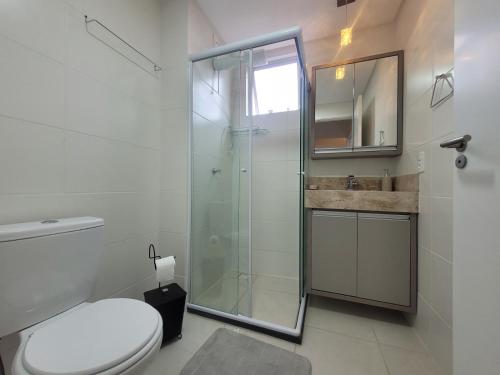 um banheiro com box de vidro e vaso sanitário em Apartamento novo, vista mar, 150m da praia em Piçarras