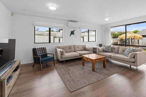 a living room with a couch and a table at The Summer Pad - Omaha Holiday Home in Warkworth