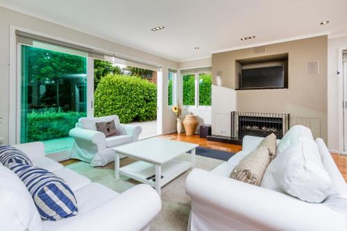 a living room with white furniture and a fireplace at Award winning house in Auckland