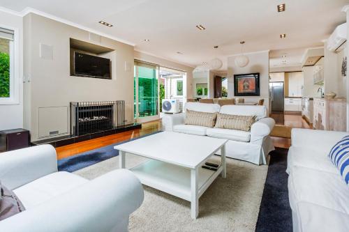 a living room with white furniture and a fireplace at Award winning house in Auckland