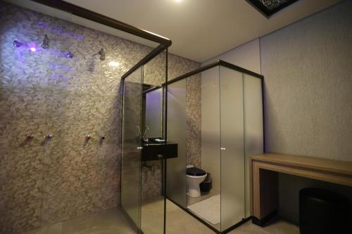 a bathroom with a glass shower with a toilet at Bellagio Motel in Foz do Iguaçu