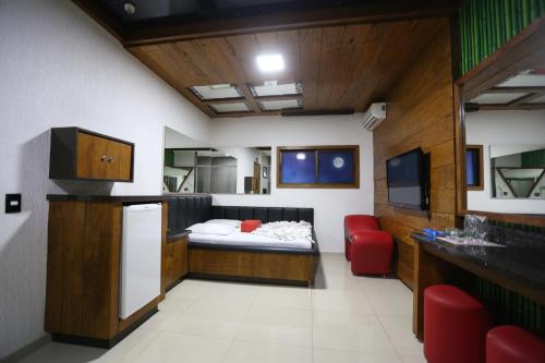 a living room with a bed and a red chair at Bellagio Motel in Foz do Iguaçu