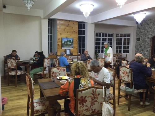 a group of people sitting at tables in a restaurant at Panorama Green View Hotel Nuwara Eliya in Nuwara Eliya