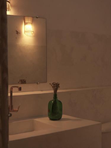 a bathroom with a green vase sitting on a sink at Vila Rita Hostel Arraial d'Ajuda in Arraial d'Ajuda