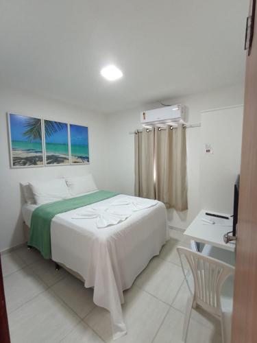 a white bedroom with a bed and a desk and a window at Pousada Villa Costeira in Maragogi
