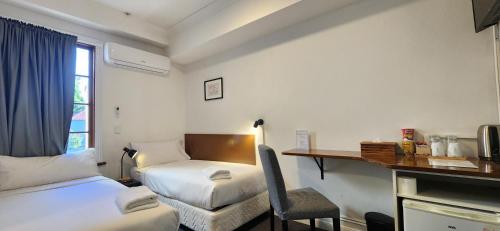 a small room with a bed and a desk with a chair at Newtown Cozy Stays in Sydney