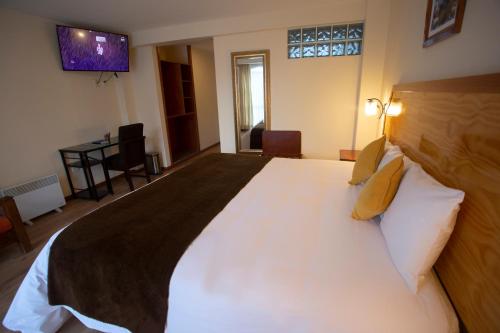 a bedroom with a large white bed with pillows at Sol Plaza Hotel in Puno