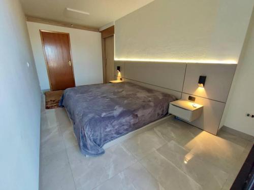 a bedroom with a bed and two night stands in it at Sobrado Luxo com Hidromassagem, Terraço e Lareira in Maringá