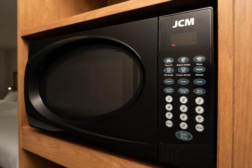 a black microwave oven sitting on a wooden shelf at Fairfield by Marriott Inn & Suites Anaheim Los Alamitos in Los Alamitos