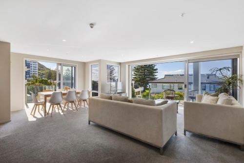 a living room with couches and a table and chairs at Sun filled & Spacious with Ocean Views & beach in Mount Maunganui