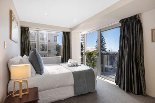a bedroom with a large bed and a large window at Sun filled & Spacious with Ocean Views & beach in Mount Maunganui