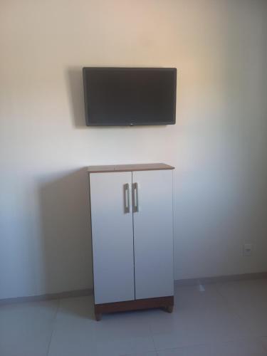 a white cabinet with a flat screen tv on a wall at Pousada Teixeira in Olímpia