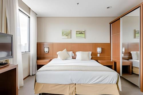a bedroom with a large bed and a television at Hospedez - Flat Osasco Trade Center in Osasco
