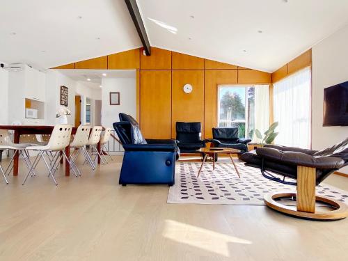 a living room with chairs and a table and a dining room at Waterfront villa near IKEA and Sylvia Park in Auckland