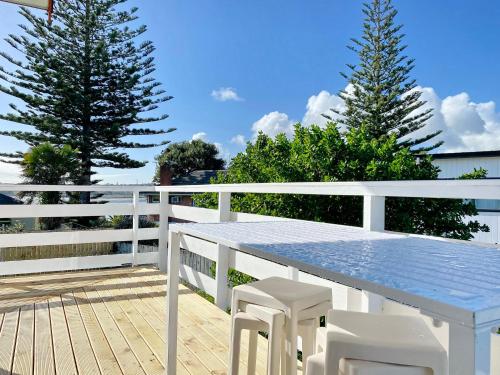 a table and chairs on a deck with two trees at Waterfront villa near IKEA and Sylvia Park in Auckland