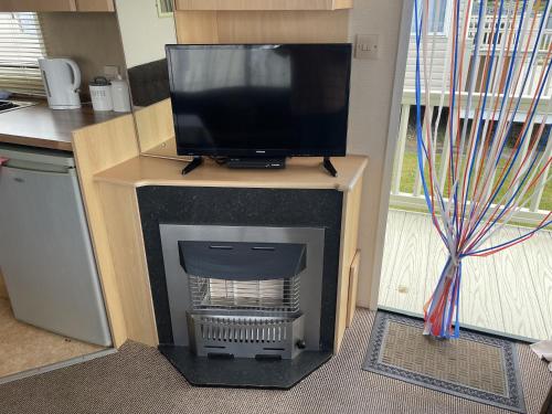 a living room with a fireplace with a tv on top at 4 Bed Lodge Sleeps 8 - Pet Friendly Parking in Skegness