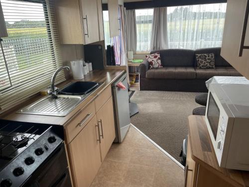 a small kitchen and living room with a couch at 4 Bed Lodge Sleeps 8 - Pet Friendly Parking in Skegness