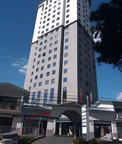 a tall white building with a bridge in front of it at Hospedez - Flat Osasco Trade Center in Osasco