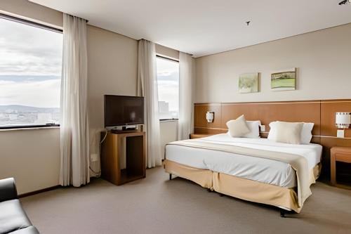 a hotel room with a large bed and a television at Hospedez - Flat Osasco Trade Center in Osasco