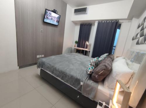 a bedroom with a bed and a tv on a wall at Pakuwon Mall Orchard ComFy New Apartemen with Wifi in Surabaya