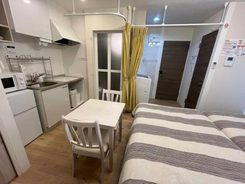 two beds in a room with a table and a kitchen at Cozy INN 西品川201 in Tokyo